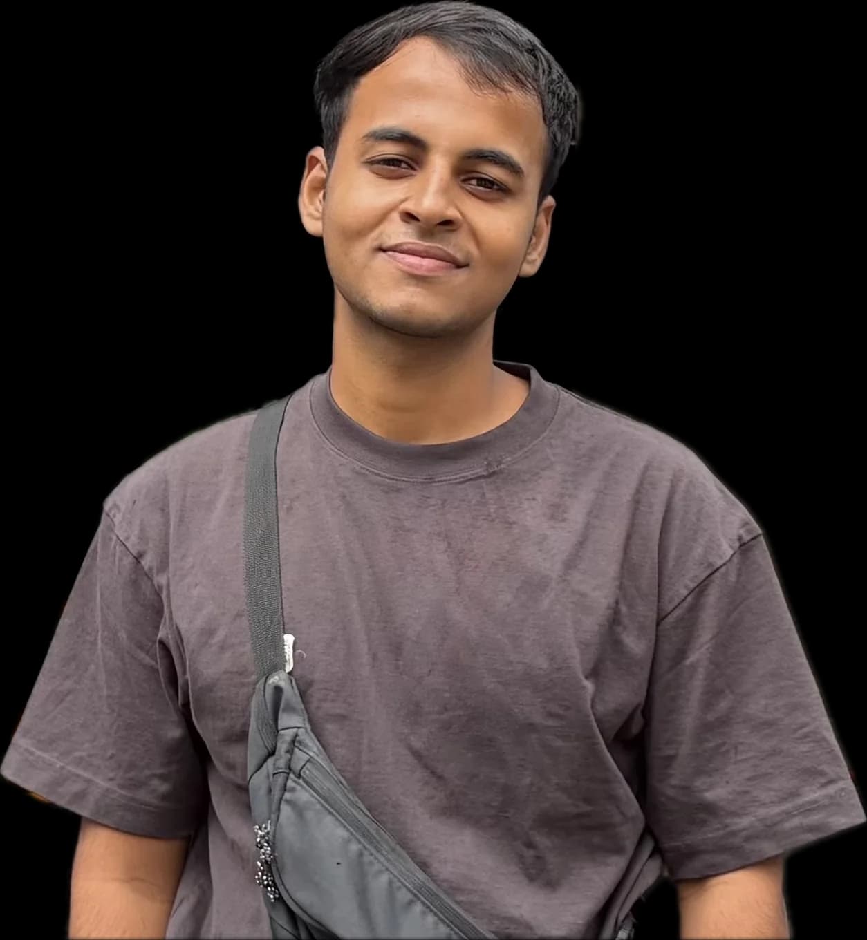 Yash Varma, smiling, in a brown t-shirt with a sling bag over one shoulder